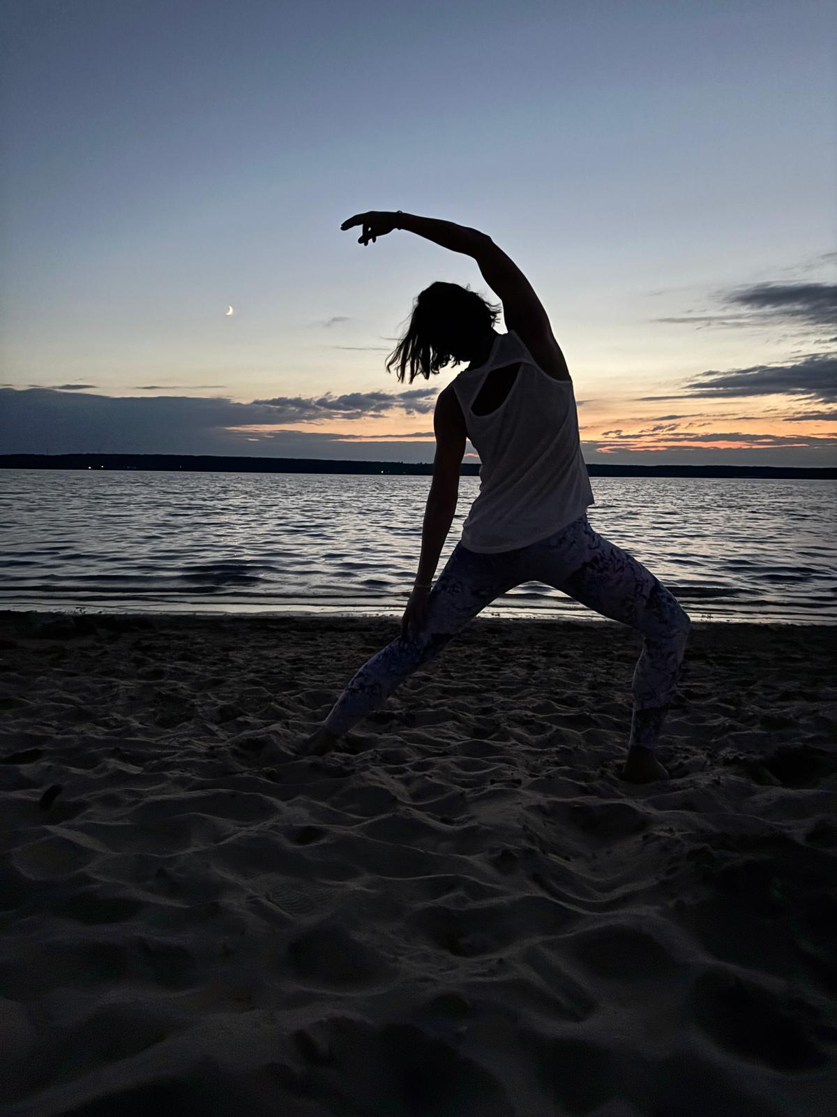 Frau bei einer Yoga-Übung am abendlichen Strand